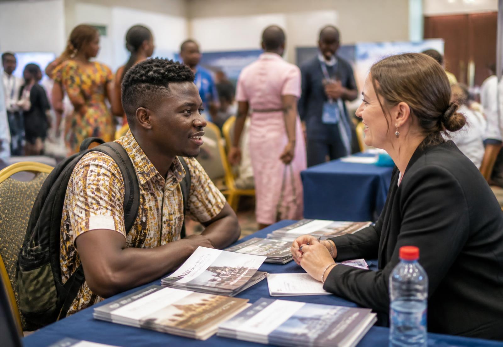A Ghanaian student in conversation with a university representative at an education expo stand