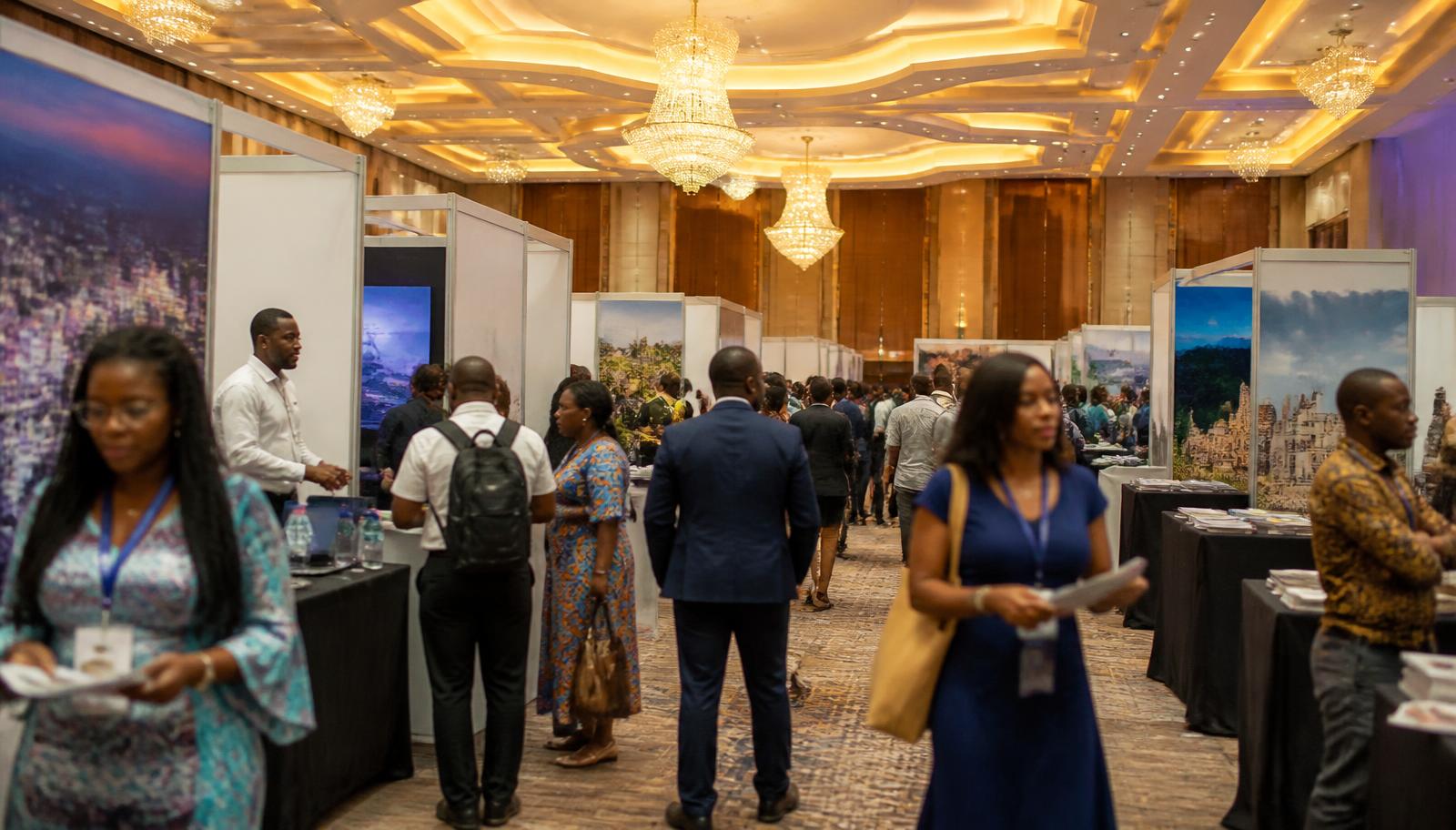 Attendees moving between exhibition stands inside a hotel ballroom in Accra